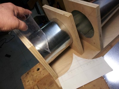 tracing the inlet hole; the paper pattern is lying on the bench.